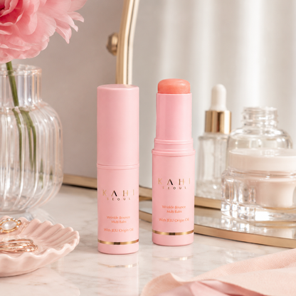 KAHI Wrinkle Bounce Multi Balm displayed on a bathroom vanity with mirror, skincare bottles, and soft floral styling.